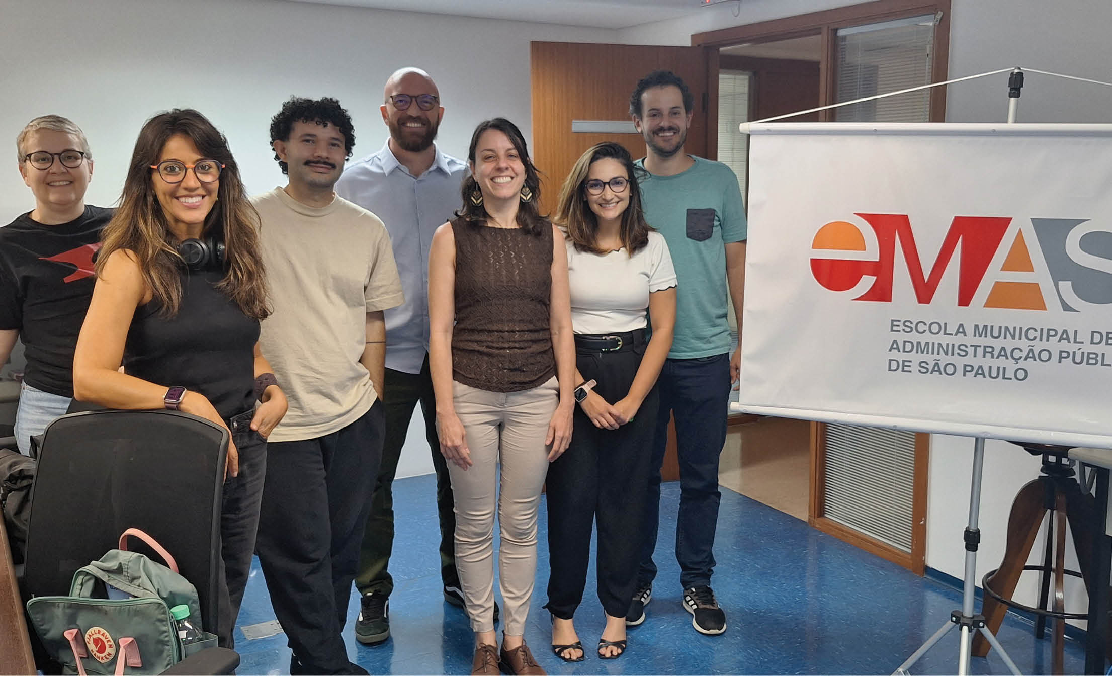 A group of people standing in front of a sign. Description generated by AI