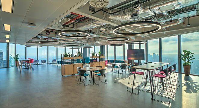 A large room with a lot of tables and chairs. Description generated by AI