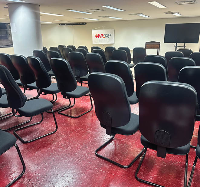A row of black chairs are lined up in a room. Description generated by AI