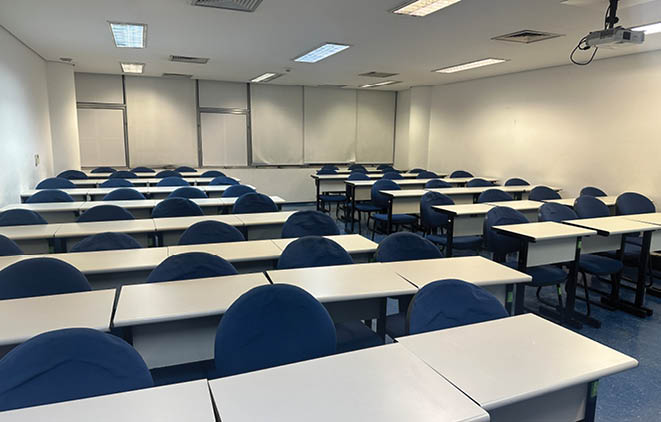 A classroom with many blue chairs and tables. Description generated by AI