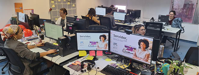 A group of people working on computers in an office. Description generated by AI